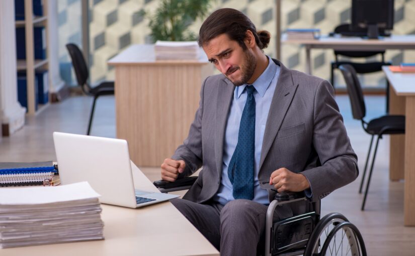 man in coat and tie with man bun using wheelchair in office